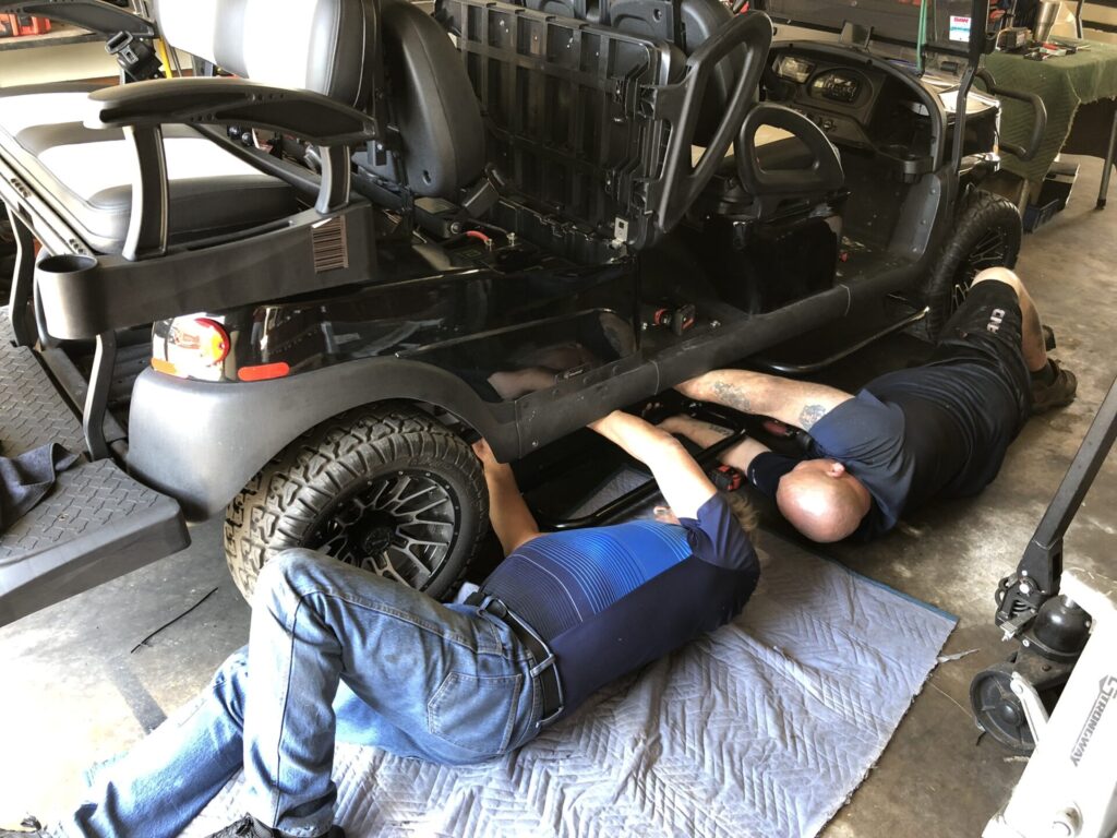 Expert repairmen repairing a black golf cart in Austin